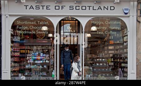 Royal Mile, Édimbourg, Écosse, Royaume-Uni. 18 mars 2020. Les touristes asiatiques portant des masques pour donner la protection contre le coronavirus sortie d'une boutique touristique dans une très calme Edinburgh's High Street. Banque D'Images