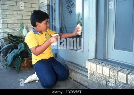 Austin Texas USA: Hispanique garçon de huit ans faisant des corvées autour de la maison. M. ©Bob Daemmrich Banque D'Images