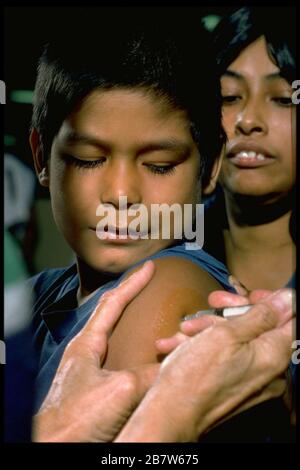 Austin Texas USA: Un garçon d'âge scolaire se trouve sur les genoux de la mère tout en obtenant une balle dans le bras à une clinique d'inoculation pour les enfants avant le début de l'année scolaire. M. ©Bob Daemmrich Banque D'Images