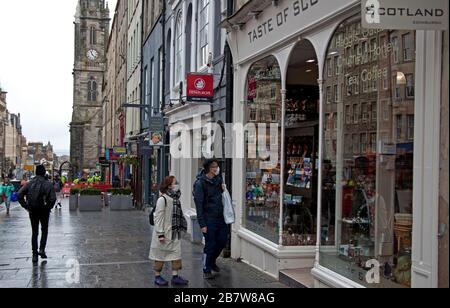 Royal Mile, Édimbourg, Écosse, Royaume-Uni. 18 mars 2020. Les touristes asiatiques portant des masques pour donner la protection contre le coronavirus sortie d'une boutique touristique dans une très calme Edinburgh's High Street. Banque D'Images