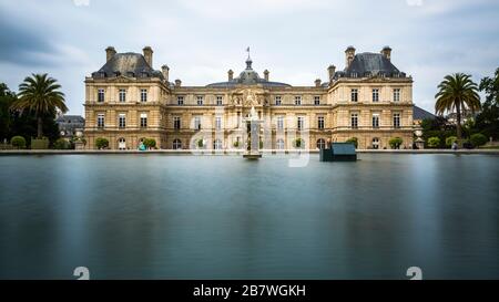 Une longue exposition du Palais du Luxembourg dans les jardins du Luxembourg à Paris, France en une journée nuageux avec le lac du jardin en premier plan. Banque D'Images