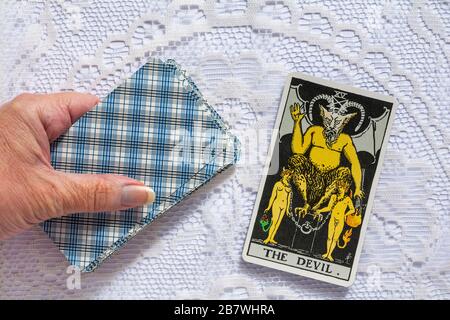 Tenue à la main Rider Tarot cartes conçues par Pamela Colman Smith sous la supervision d'Arthur Edward Waite avec la carte du diable tarot retourné Banque D'Images