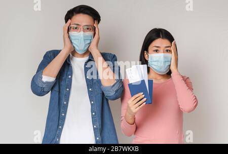 Couple chinois paniqué portant des masques médicaux Holding passeports et des billets Banque D'Images