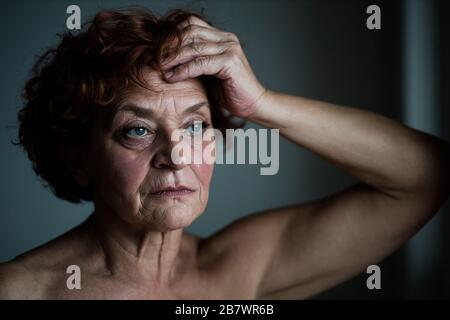 Femme mûre par la fenêtre pensant à la vie Banque D'Images