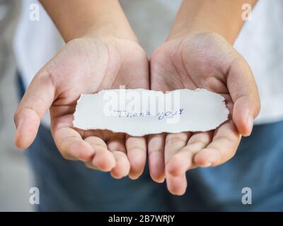Le garçon tenant un morceau de papier avec le mot Merci dans la paume se sentir heureux. Banque D'Images