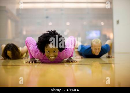 Portrait of a smiling young woman doing press ups à l'intérieur d'une salle de sport. Banque D'Images