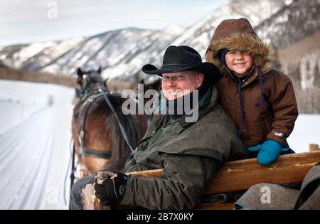 Père et fils souriants assis sur un chariot à cheval. Banque D'Images