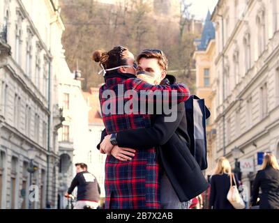 Ljubljana, Slovénie; 12.03.2020. Un jeune couple effrayé qui embrasse un masque de protection du visage dans le centre-ville depuis le nouveau coronavirus SRAS-CoV-2. Banque D'Images