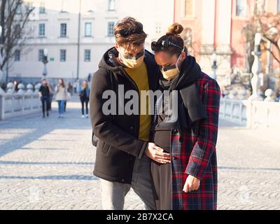 Un jeune couple portant un masque de protection du visage dans le centre-ville inquiet depuis l'apparition du nouveau coronavirus SRAS-COV-2 (Covid 19). La femme est enceinte. Banque D'Images
