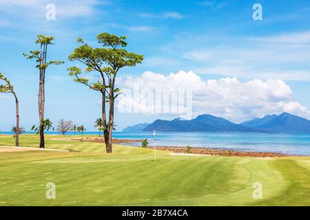 Vue sur le 8ème green d'entrée à la mer d'Andaman et l'île d'Anak Dai au parcours de golf Rainforest, au Club d'Els, à Teluk Dai, Langkawi, Banque D'Images