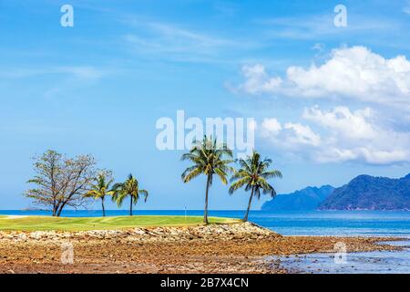 Vue sur le 16ème green de mise à la mer d'Andaman et l'île d'Anak Datai au parcours de golf Rainforest, le Club d'Els, Teluk Datai, Langkawi Banque D'Images