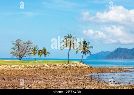 Vue sur le 16ème green de mise à la mer d'Andaman et l'île d'Anak Datai au parcours de golf Rainforest, le Club d'Els, Teluk Datai, Langkawi Banque D'Images