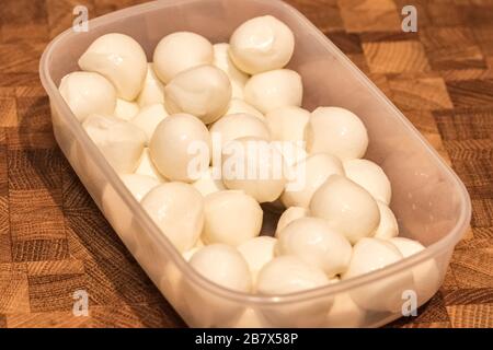 Mini mozzarella boules de fromage dans une plaque en plastique sur une table en bois. Ingrédient pour la salade Banque D'Images