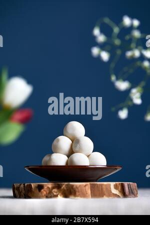 La nourriture nationale kazakh et kirghize kurt boules salées blanches du fromage sec autour des fleurs pendant le festival de Nauryz à fond bleu foncé. Espace libre pour y Banque D'Images