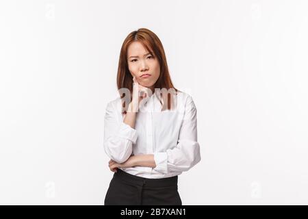 Une jeune femme asiatique réfléchie et sérieuse qui réfléchit, qui a des difficultés à préparer son plan, se penche sur la frognure et affament l'appareil photo agacé Banque D'Images