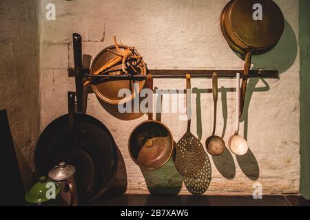 Ustensiles de cuisine vintage : casseroles et louches de cuisine accrochées sur un mur de briques blanches Banque D'Images