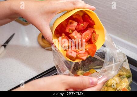 Mains féminines verser les tomates fraîchement hachées dans un sac de légumes. Cuisson. Espace de copie Banque D'Images