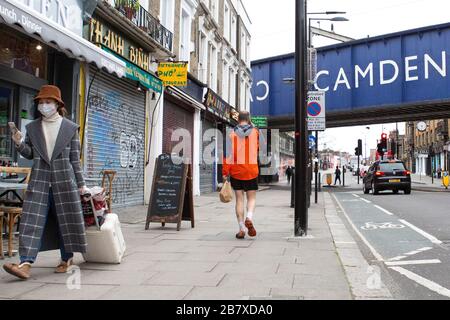 Une femme avec un masque marche à travers le marché de Camden mercredi 18 mars 2020, comme la propagation du Coronavirus (COVID-19) effets Londres Banque D'Images