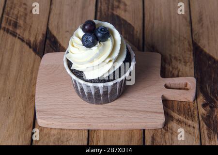 Muffin au chocolat avec crème blanche et myrtille. Banque D'Images