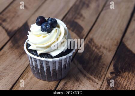 Muffin au chocolat avec crème blanche et myrtille. Banque D'Images