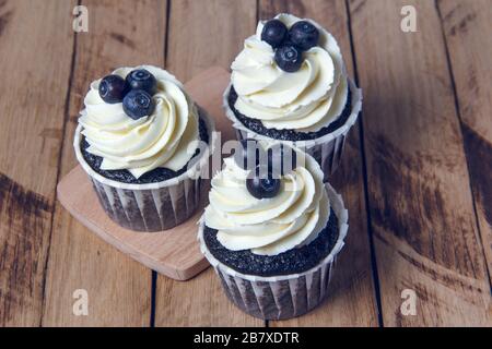 Cupcakes au chocolat avec crème blanche et myrtilles. Banque D'Images