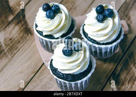 Cupcakes au chocolat avec crème blanche et myrtilles. Banque D'Images