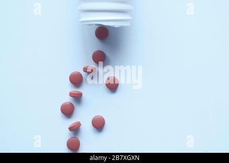 Les pilules blanches débordent d'une bouteille de pilules blanches renversée. Banque D'Images