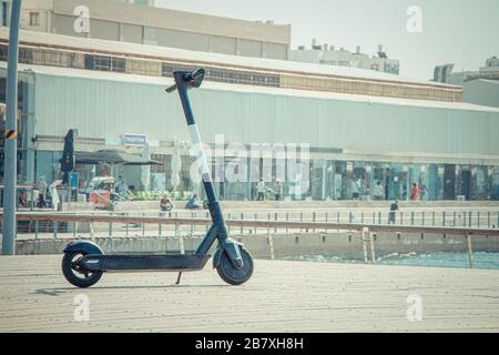 Parking en scooter électrique noir sur une terrasse dans le quartier commercial du port de tel-Aviv le jour ensoleillé de l'été. Gros plan de la mise au point sélective avec espace de copie. Banque D'Images