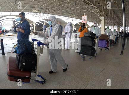 Farwaniya, Koweït. 18 mars 2020. Les passagers et les travailleurs égyptiens des combinaisons de protection sont vus à l'aéroport international du Koweït, dans le gouvernorat de Farwaniya, au Koweït, le 18 mars 2020. Le Koweït a expulsé mercredi 96 Égyptiens dans leur pays d'origine, a déclaré Mariam Al-Aqeel, Ministre koweïtien des affaires sociales et du travail et Ministre d'État chargé des affaires économiques. Le Koweït a signalé 12 nouveaux cas de COVID-19 au cours des dernières 24 heures, portant à 142 le nombre total de cas confirmés dans le pays, a annoncé mercredi le Ministère de la santé. Crédit: Xinhua/Alay Live News Banque D'Images