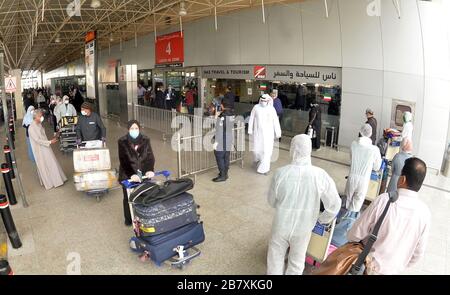 Farwaniya, Koweït. 18 mars 2020. Les passagers et les travailleurs égyptiens des combinaisons de protection sont vus à l'aéroport international du Koweït, dans le gouvernorat de Farwaniya, au Koweït, le 18 mars 2020. Le Koweït a expulsé mercredi 96 Égyptiens dans leur pays d'origine, a déclaré Mariam Al-Aqeel, Ministre koweïtien des affaires sociales et du travail et Ministre d'État chargé des affaires économiques. Le Koweït a signalé 12 nouveaux cas de COVID-19 au cours des dernières 24 heures, portant à 142 le nombre total de cas confirmés dans le pays, a annoncé mercredi le Ministère de la santé. Crédit: Xinhua/Alay Live News Banque D'Images