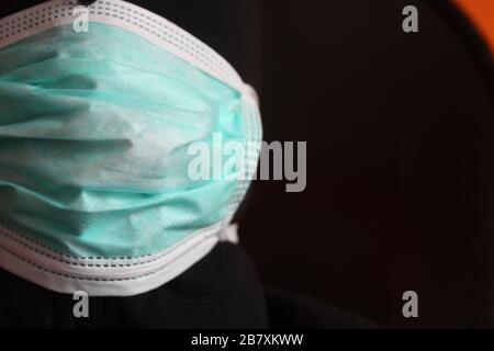 Une personne mystérieuse à capuche non reconnaissable avec un sweat-shirt sombre porte un masque chirurgical bleu normal en italie Banque D'Images