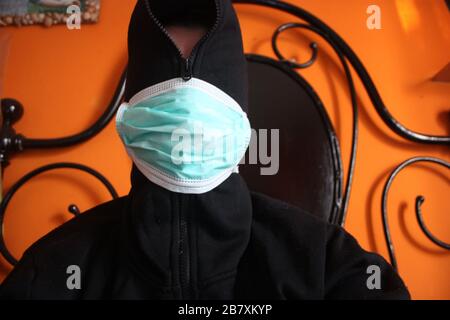 Une personne mystérieuse à capuche non reconnaissable avec un sweat-shirt sombre porte un masque chirurgical bleu normal en italie Banque D'Images