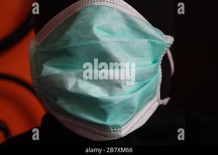 Une personne mystérieuse à capuche non reconnaissable avec un sweat-shirt sombre porte un masque chirurgical bleu normal en italie Banque D'Images