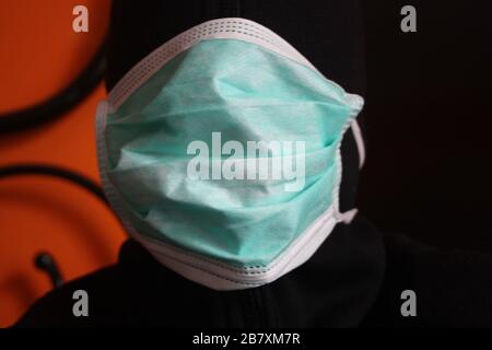 Une personne mystérieuse à capuche non reconnaissable avec un sweat-shirt sombre porte un masque chirurgical bleu normal en italie Banque D'Images