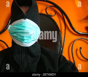 Une personne mystérieuse à capuche non reconnaissable avec un sweat-shirt sombre porte un masque chirurgical bleu normal en italie Banque D'Images