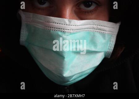 Une personne mystérieuse à capuche non reconnaissable avec un sweat-shirt sombre porte un masque chirurgical bleu normal en italie Banque D'Images