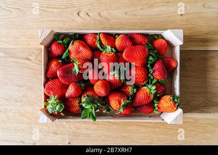 Une boîte de fruits remplie de fraises vues d'en haut sur une table en bois Banque D'Images