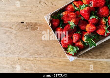 Une boîte de fruits remplie de fraises vues d'en haut sur une table en bois Banque D'Images