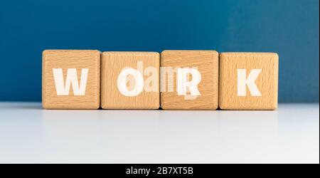 Le mot TRAVAIL sur des cubes de bois. Blocs en bois sur fond bleu. Concept d'affaires et de carrière. Banque D'Images