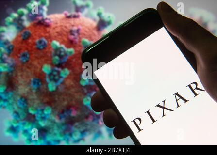 Dans cette photo, le studio américain de cinéma d'animation informatique appartenant à Disney, Pixar, logo vu sur un smartphone avec un modèle d'ordinateur du Coronavirus COVID-19 sur le fond. Banque D'Images