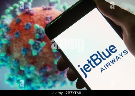 Sur cette photo, le logo JetBlue Airways de la compagnie aérienne américaine à bas prix est affiché sur un smartphone avec un modèle d'ordinateur du coronavirus COVID-19 en arrière-plan. Banque D'Images