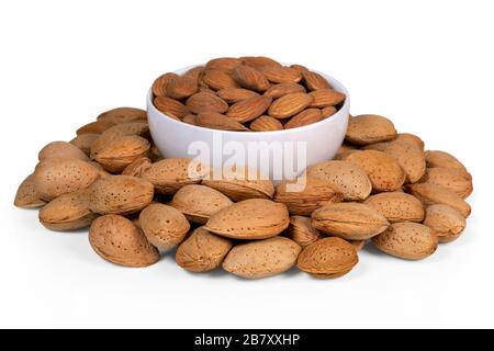 Amandes pelées dans un bol blanc entouré d'amandes brutes en coquille. Isolé sur fond blanc. Banque D'Images