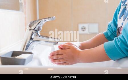 Gros plan des mains savonnelles d'un enfant lavées sous l'eau courante dans un évier Banque D'Images