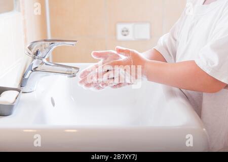 Gros plan des mains savonnelles d'un enfant lavées sous l'eau courante dans un évier Banque D'Images