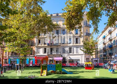 Les enfants et les parents jouent dans un parc urbain clos avec de l'herbe artificielle dans le centre de Nice, France, sur la Côte d'Azur. Banque D'Images