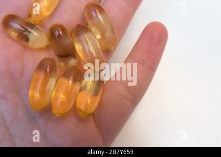 Vitaminen Omega 3 huile de poisson dans les capsules en main sur fond beige. Banque D'Images