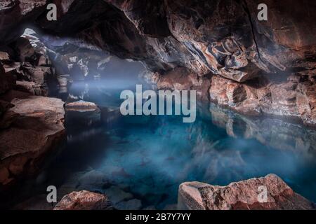 Magnifique piscine géothermique turquoise claire avec brume sur le dessus à l'intérieur de la grotte volcanique à Grjotagja, Islande Banque D'Images