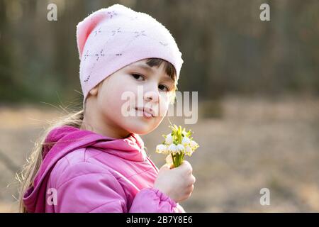 Portrait d'une jeune fille heureuse tenant un bouquet de fleurs de neige printanière plein air. Banque D'Images