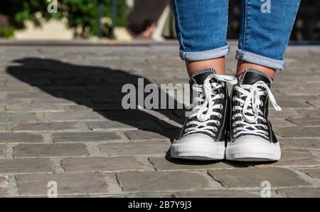 Chartres, France - 2 septembre 2019 : Droit de la partie inférieure de l'adolescent, les jambes en jeans et baskets Converse All Star dans une rue pavée. Banque D'Images