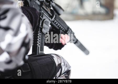 Un militaire en hiver camouflage avec un fusil se prépare à une attaque. Gros plan. Banque D'Images